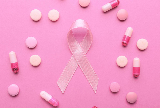 Pink ribbon and pills on color background. Breast cancer awareness concept - Fotoğraf, Görsel