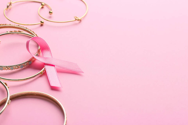 Pink ribbon and bijouterie  on color background. Breast cancer awareness concept - Foto, Imagem