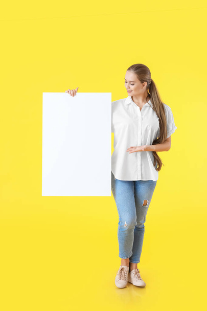 Beautiful young woman with blank poster on color background - Valokuva, kuva