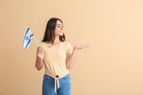 Young woman with the flag of Israel showing something on color background - Φωτογραφία, εικόνα