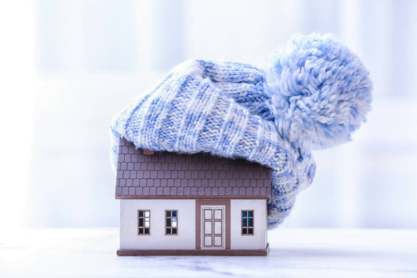 Figure of house and warm hat on table. Concept of heating season - Photo, Image