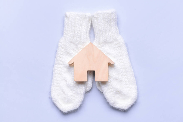 Figure of house and warm mittens on light background. Concept of heating season - Photo, Image