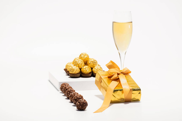 Golden kääritty suklaa makeisia lahjapakkauksessa ja samppanjalasi - Valokuva, kuva