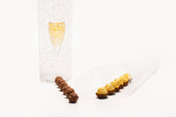 wrapped and unwrapped chocolate and hazelnut sweets with decorations and a glass of champagne - Fotoğraf, Görsel