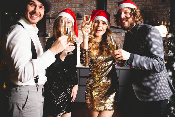 Enjoying New Year party. Group of beautiful young people in Santa hats dancing and looking happy. - Foto, imagen
