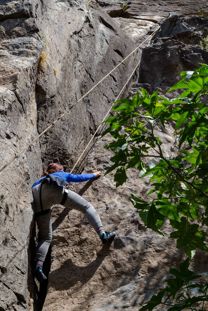 woman with a rope engaged in the sports of rock climbing on the rock - Photo, Image
