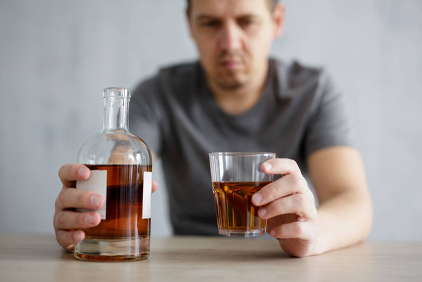 Alkoholismus, Probleme und Depressionen - Großaufnahme von Glas und Flasche Whiskey in männlicher Hand - Foto, Bild