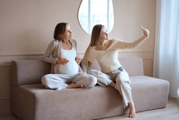 multiethnic girlfriends and happy pregnant woman taking selfie on smartphone . High quality photo. - Foto, imagen