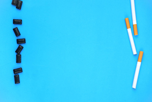 Fondo azul con cigarrillos y almohadillas de goma negras - Foto, Imagen