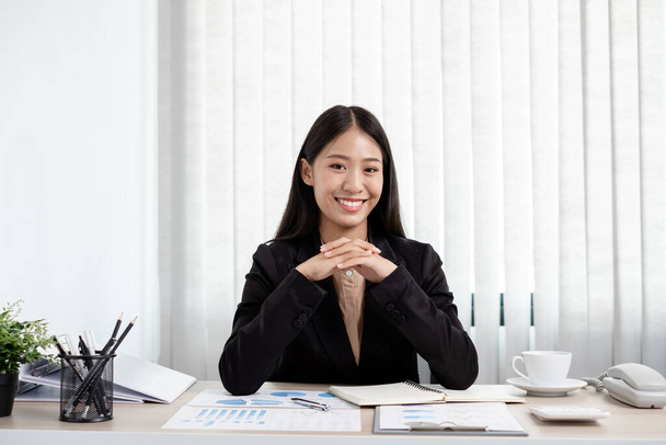 Aziatische zakenvrouwen zitten aan hun bureau en berekenen financiële grafieken met resultaten over hun investeringen, plannen een succesvol groeiproces in het kantoor. - Foto, afbeelding