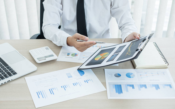 Liikemies käsi istuu pöytiensä ääressä ja laskee taloudelliset kaaviot, jotka osoittavat tulokset sijoitusten suunnittelee prosessin onnistuneen liiketoiminnan kasvun. - Valokuva, kuva
