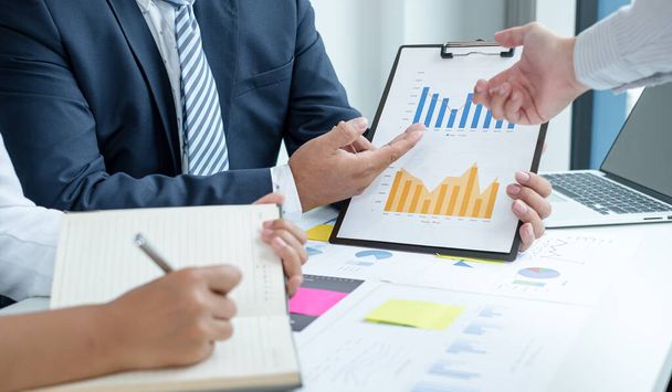 Drei Unternehmensführer sprechen über Diagramme, Finanzgrafiken, die Ergebnisse zeigen, analysieren und berechnen Planungsstrategien, Unternehmenserfolg aufbauende Prozesse. - Foto, Bild