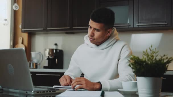 Hombre negro con capucha blanca trabajando en casa en el ordenador - Metraje, vídeo