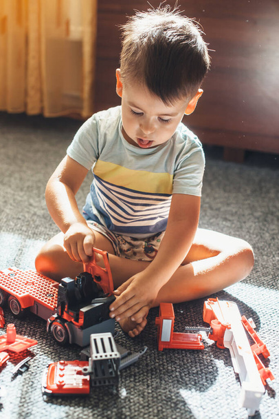 Caucasian boy in pajama is playing on the floor with a constructor car - Φωτογραφία, εικόνα