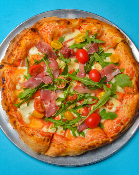 A Pepperoni pizza on a blue background isolated. Traditional Italian cuisine concept, pizza Margarita or Margherita over blue. - Фото, зображення