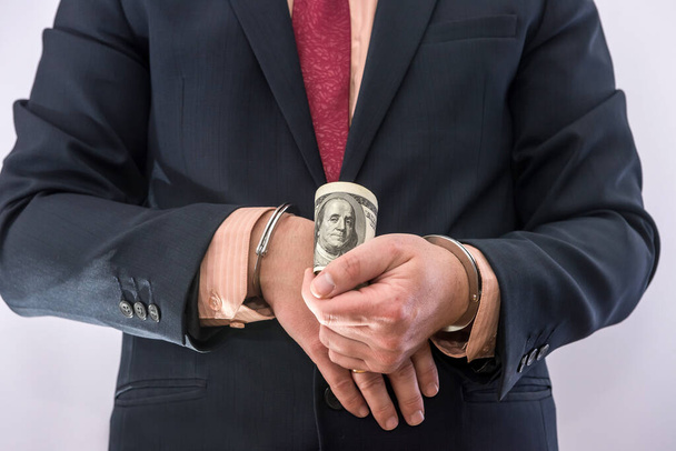 Vesztegetés vagy korrupció koncepció A férfi kezek bilincsben tartják a dollárszámlákat. büntető - Fotó, kép