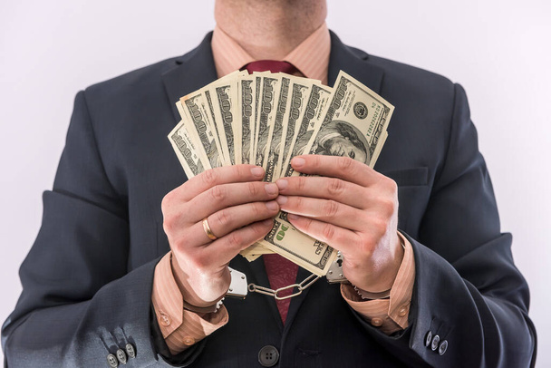 Δωροδοκία ή διαφθορά έννοια ανδρικά χέρια κατέχουν δολάρια χαρτονομίσματα σε χειροπέδες. εγκληματικό - Φωτογραφία, εικόνα