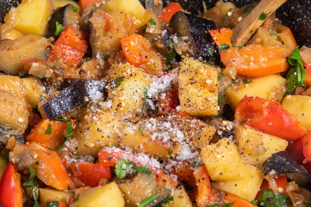 Cooking a traditional Italian vegetable stew with potatoes, eggplants and peppers in a frying pan - Neapolitan cianfotta. - Fotografie, Obrázek