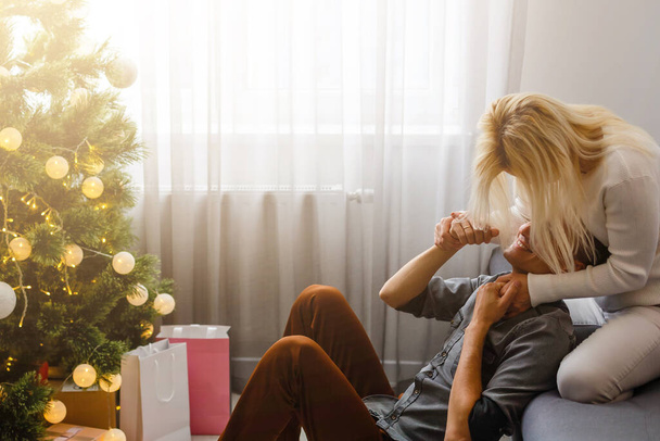 Couple Exchanging Christmas Gifts near Christmas tree. - Фото, изображение