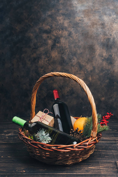 Бутылки красного и белого вина в рождественской подарочной корзине. Вино с апельсинами, чашками и елочными украшениями в коробке. Вид сверху - Фото, изображение