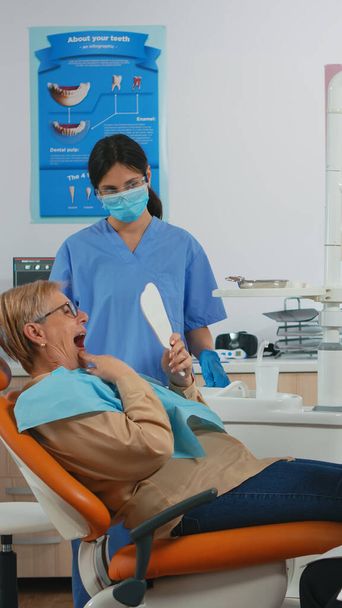 Patient liegt im Stuhl beim Zahnarzt und schaut in den Spiegel - Foto, Bild