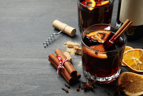 Bottle of wine, cups of mulled wine and ingredients on wooden background - Фото, изображение
