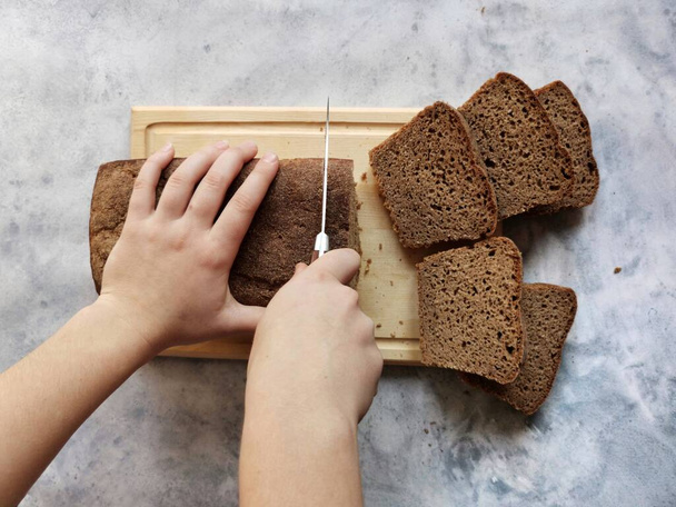 rozskenyérbe vágott női kéz, kovászból készült házi kenyér - Fotó, kép