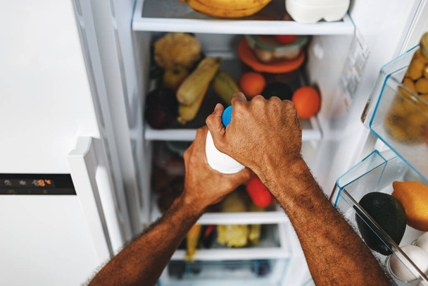 Male hands taking bottle of milk from a fridge - Photo, Image