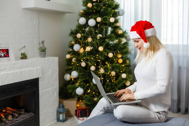 Noel ağacının yanında dizüstü bilgisayar kullanan kadın. - Fotoğraf, Görsel