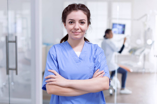 Портрет стоматологічної медсестри в стоматологічному прийомі з схрещеними руками
 - Фото, зображення