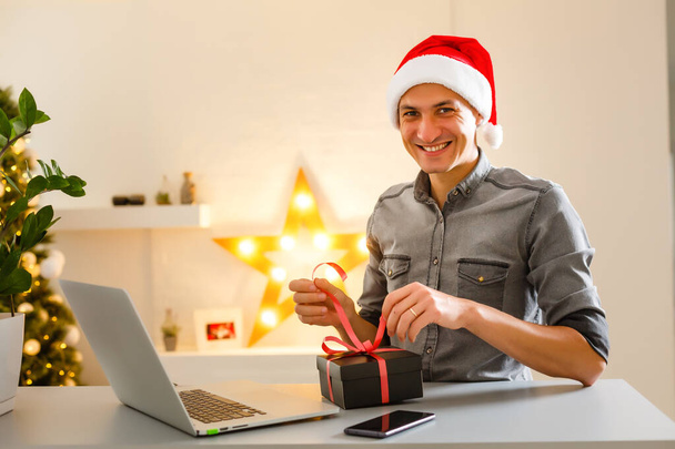 Młody człowiek robi zakupy online z kartą kredytową w domu na święta. Koncepcja zakupów świątecznych. - Zdjęcie, obraz