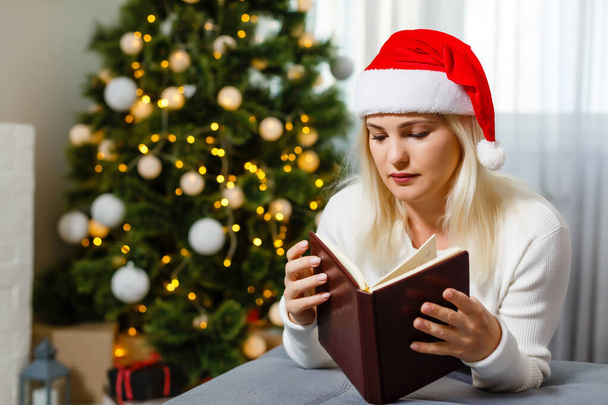 Egy nő ül egy karácsonyfa mellett egyedül - Fotó, kép