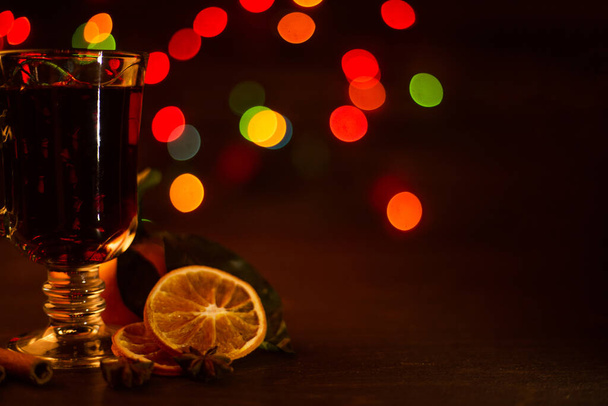 Mulled wine with cinnamon sticks and orange over holiday christmas lights background - Foto, Imagem