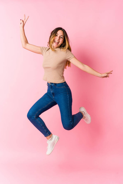 Young caucasian blonde woman jumping on pink background - Photo, Image