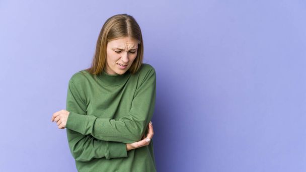 Young blonde woman isolated on purple background massaging elbow, suffering after a bad movement. - Photo, Image