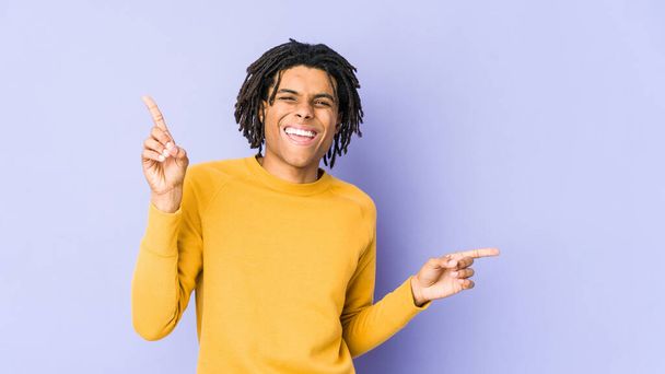 Jonge zwarte man draagt rasta kapsel wijzend naar verschillende kopieerruimtes, kiezen een van hen, tonen met de vinger. - Foto, afbeelding