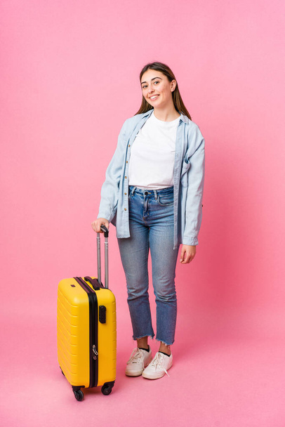 Young caucasian woman going to traveler isolated on pink background - 写真・画像