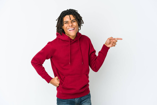 Young african american rasta man smiling cheerfully pointing with forefinger away. - 写真・画像