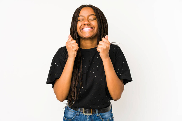Молода афро-американська жінка, ізольована на білому фоні, піднімає кулак, відчуває себе щасливою і успішною. Концепція перемоги. - Фото, зображення