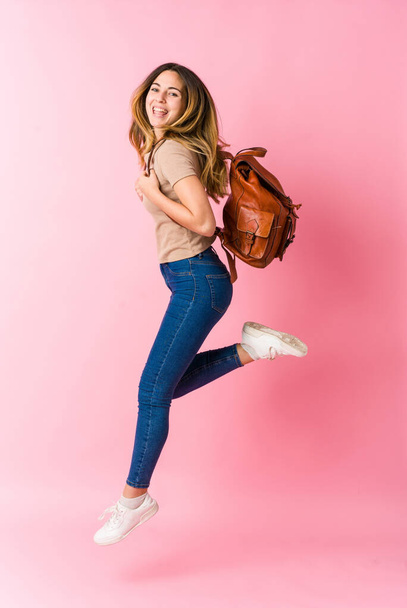 Young caucasian student woman jumping wih coffe on pink background - Foto, Imagen