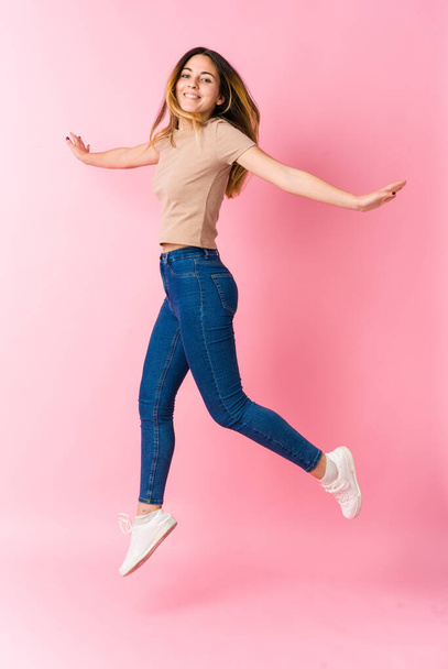 Giovane studentessa caucasica saltando wih caffè su sfondo rosa - Foto, immagini