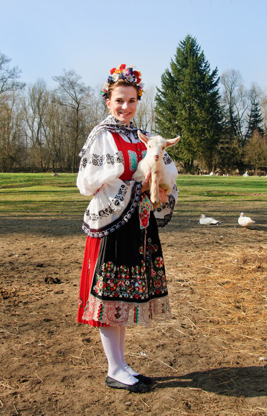 Улыбающаяся девушка в народном костюме с маленьким ягненком
 - Фото, изображение