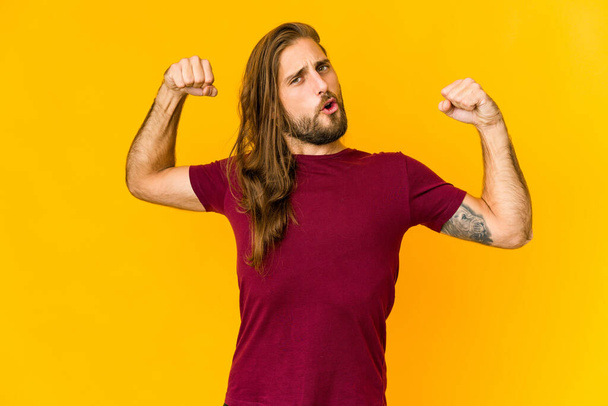 Young man with long hair look showing strength gesture with arms, symbol of power - Photo, Image