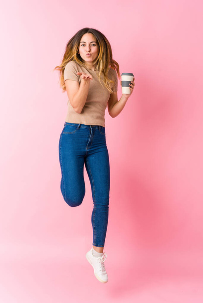 Young caucasian student woman jumping wih coffe on pink background - Zdjęcie, obraz