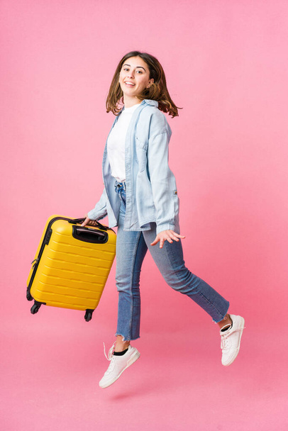 Nuori valkoihoinen nainen menossa matkustaja eristetty vaaleanpunainen tausta - Valokuva, kuva