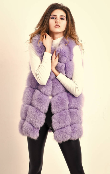Luxury fur clothes for female. Girl curly hairstyle enjoy soft warm violet furry coat. Fashion trend concept. Violet fur vest fashion clothing. Woman makeup face wear fur vest white background - Фото, зображення