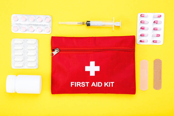 First aid kit with medical supplies on yellow background - Fotó, kép