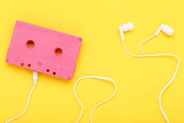 Earphones and cassette tape on yellow background - Foto, Imagen