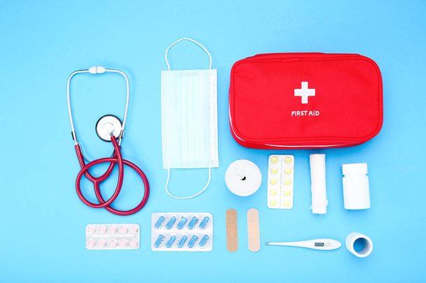 First aid kit with medical supplies on blue background - Фото, зображення