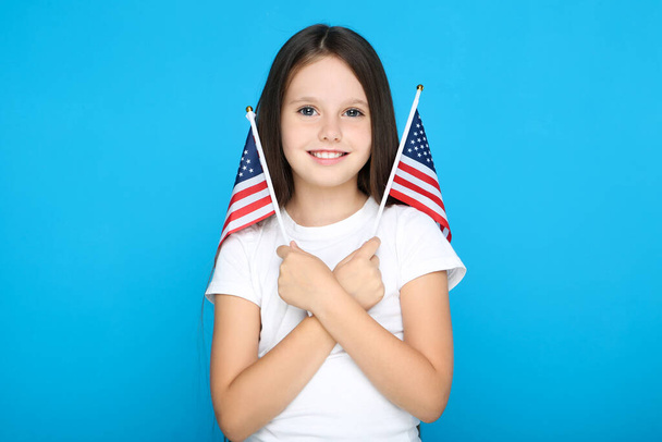 jong meisje met amerikaanse vlaggen op blauwe achtergrond - Foto, afbeelding